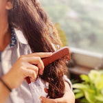 A women entangling her hair with wide tooth and fine tooth Solid wooden combs made from the beech tree.