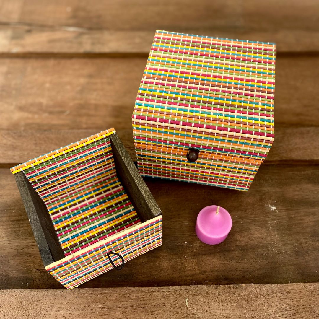 Set of 2 multicolour gift box and candle kept on side