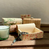 Candle near 5 bamboo gift boxes in different colours and pattern