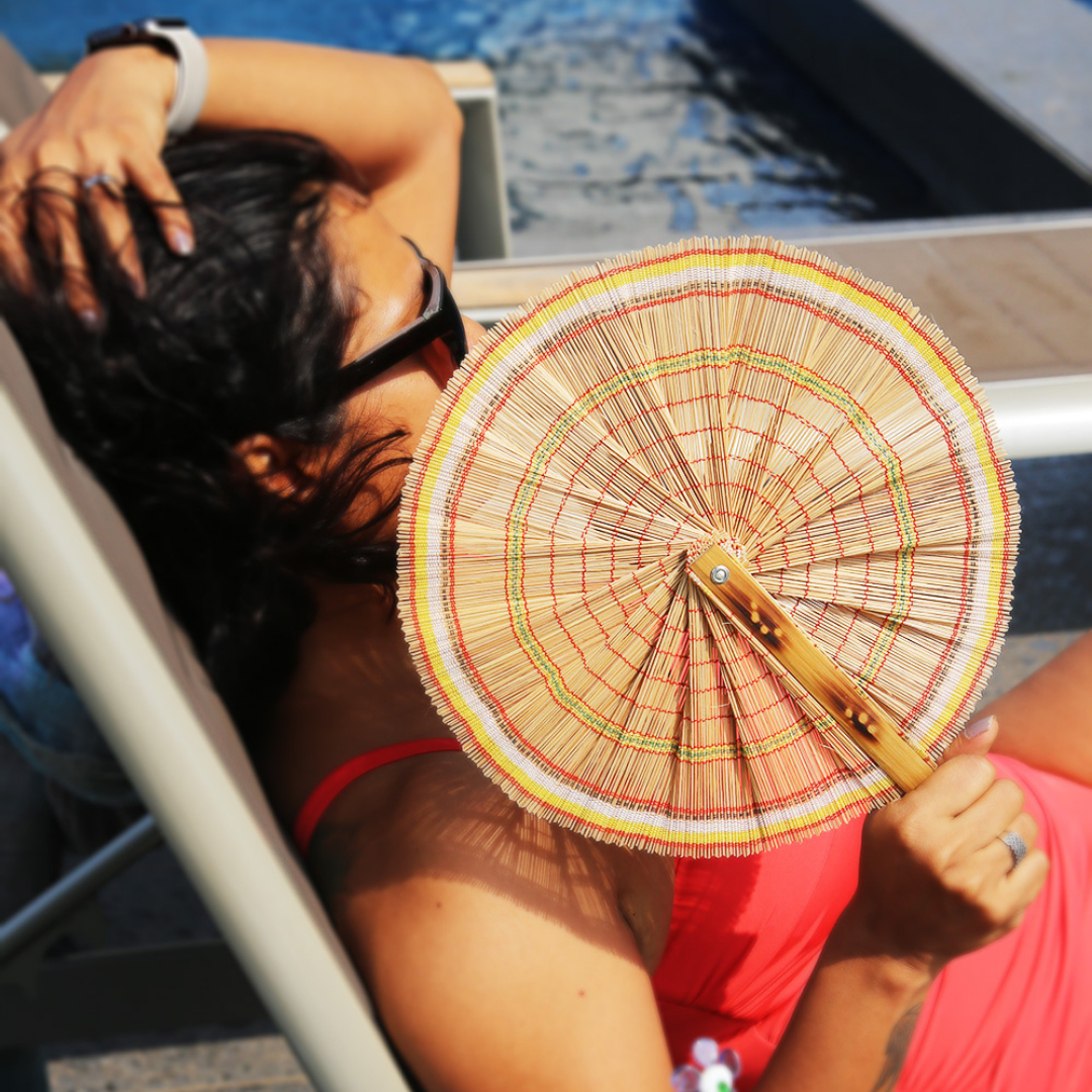 A person holding natural bamboo hand fan. 