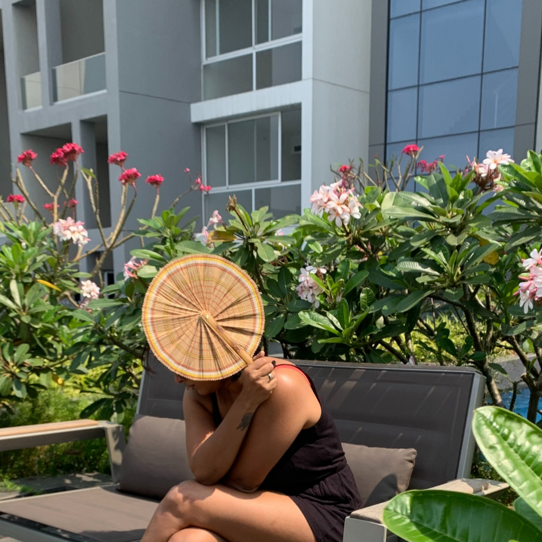 A person holding natural bamboo hand fan.