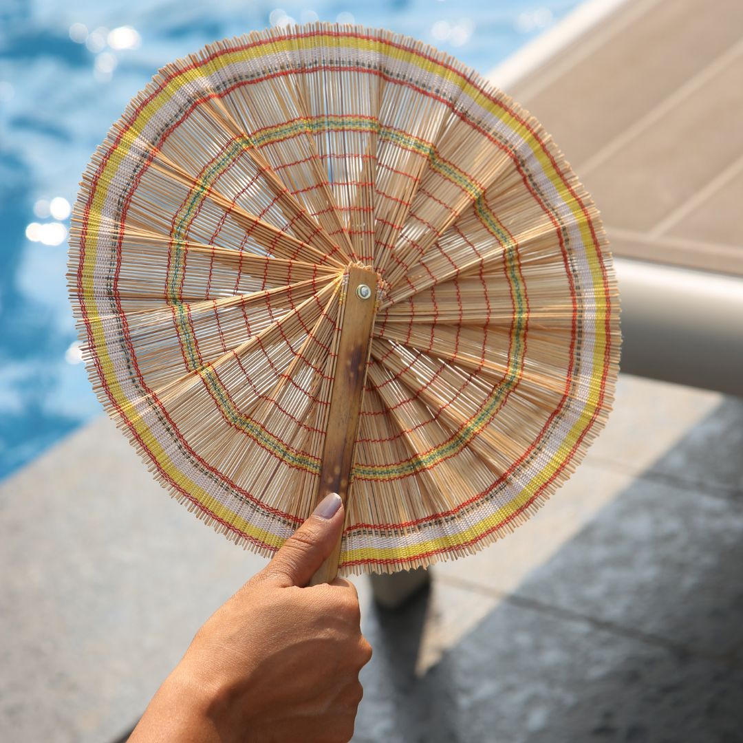 A person holding natural bamboo hand fan.
