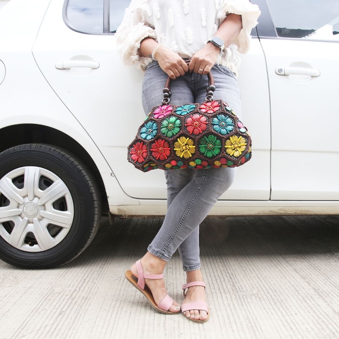 Model holding Multi colour 'Dahlia' coconut handbag car in background