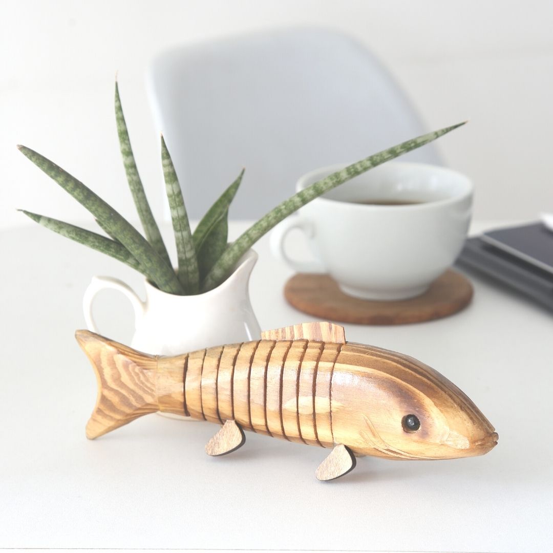 Close up of "Bubbles" Wooden Fish with plant in background.