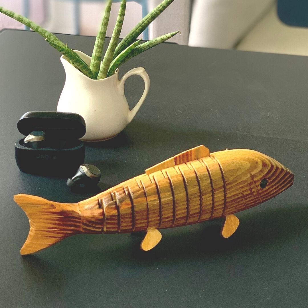 Close up of "Bubbles" Wooden Fish with plant in background. 