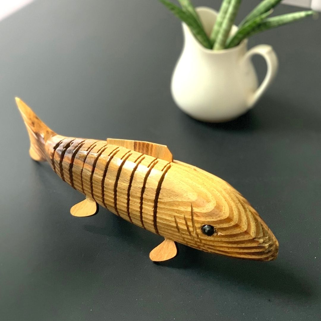 Close up of "Bubbles" Wooden Fish with plant in background.