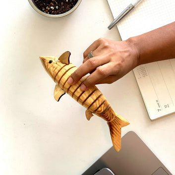 A person fidgeting with wooden toy shark