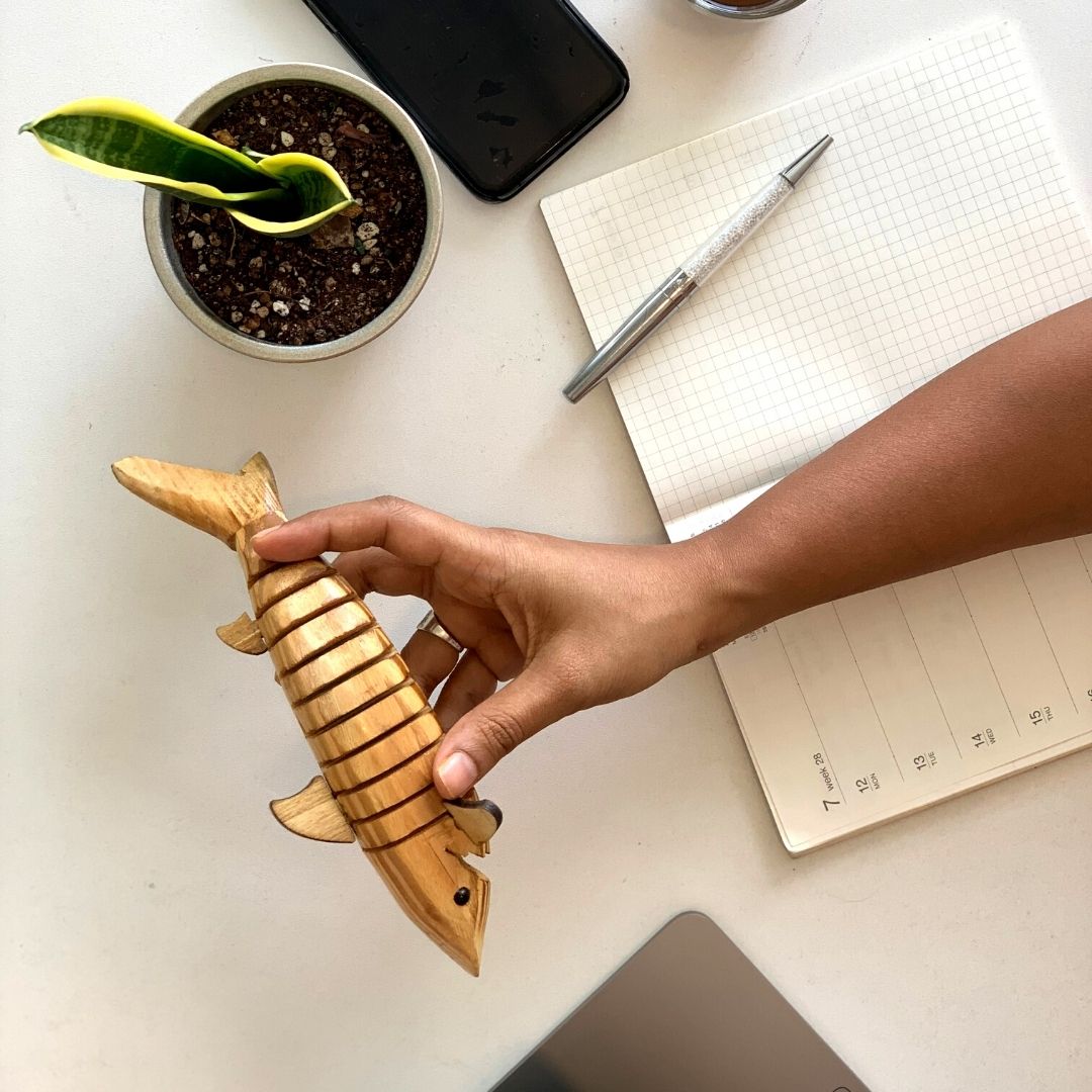 A person fidgeting with wooden toy shark